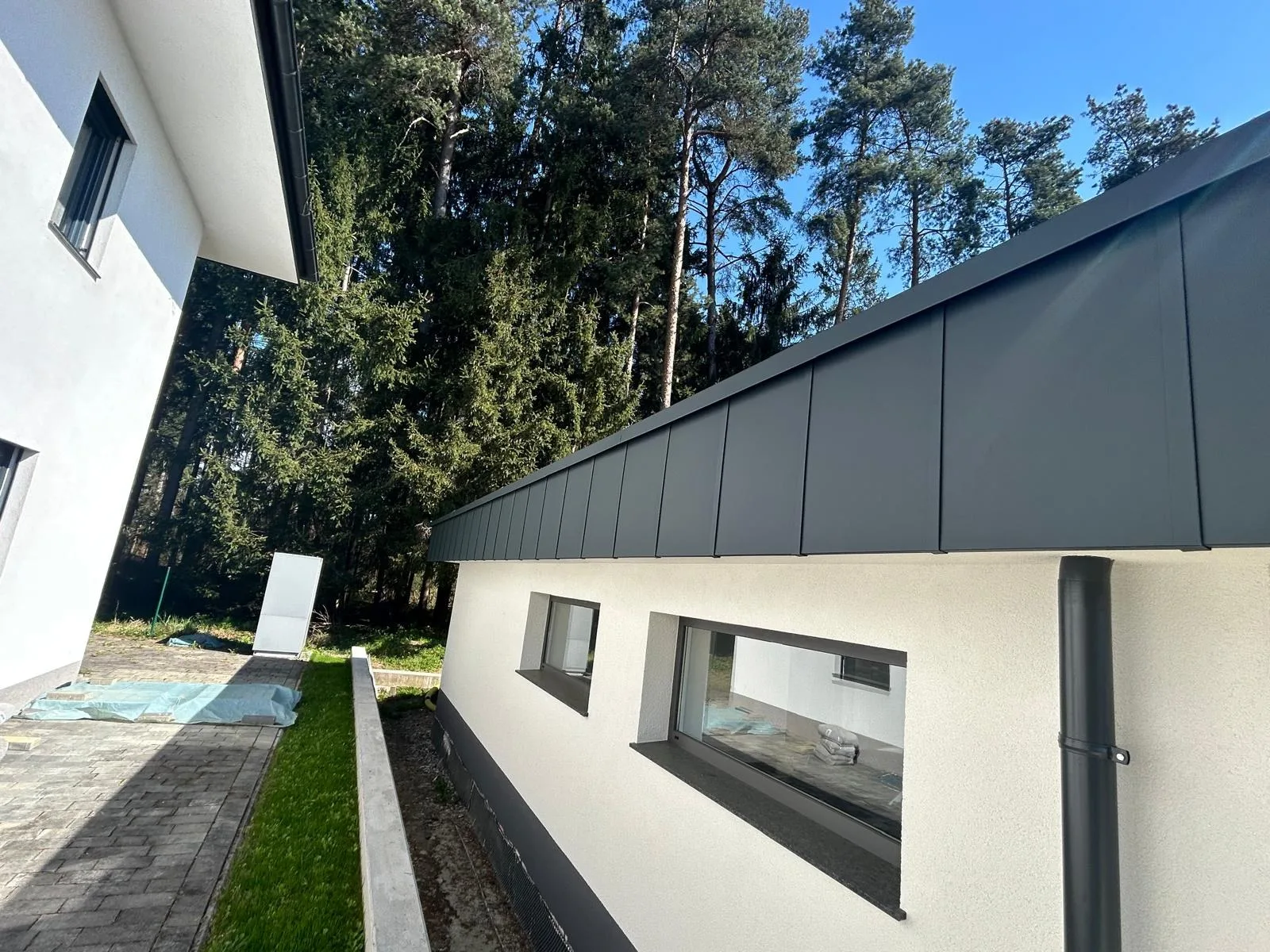 Graue Metallverkleidung mit präzise ausgeführter Dachentwässerung